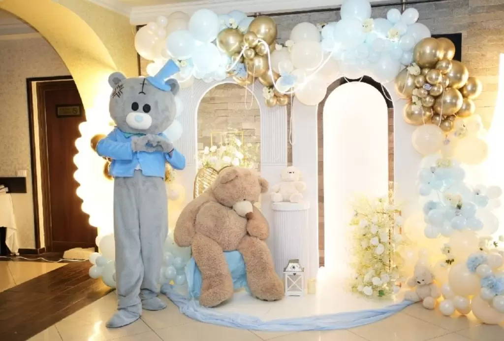 Mascota ursuleț Kids Mania lângă decorul cu baloane de la un botez