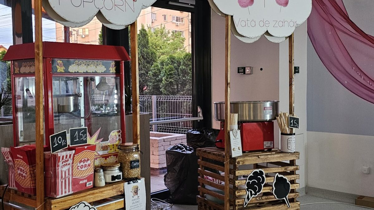 Două standuri pe paleți cu aparat pentru popcorn, aparat pentru vată de zahăr și panouri în formă de nor