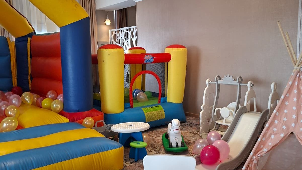 Spațiu de joacă interior cu castel gonflabil colorat, masă de colorat, tobogan și cort teepee