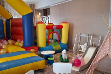 Spațiu de joacă interior cu castel gonflabil colorat, masă de colorat, tobogan și cort teepee