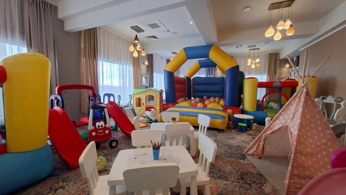 Spațiu de joacă interior cu castel gonflabil, tobogane mici, căsuță, cort teepee roz și masă pentru colorat