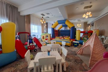 Spațiu de joacă interior cu castel gonflabil, tobogane mici, căsuță, cort teepee roz și masă pentru colorat