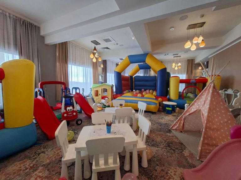 Spațiu de joacă interior cu castel gonflabil, tobogane mici, căsuță, cort teepee roz și masă pentru colorat