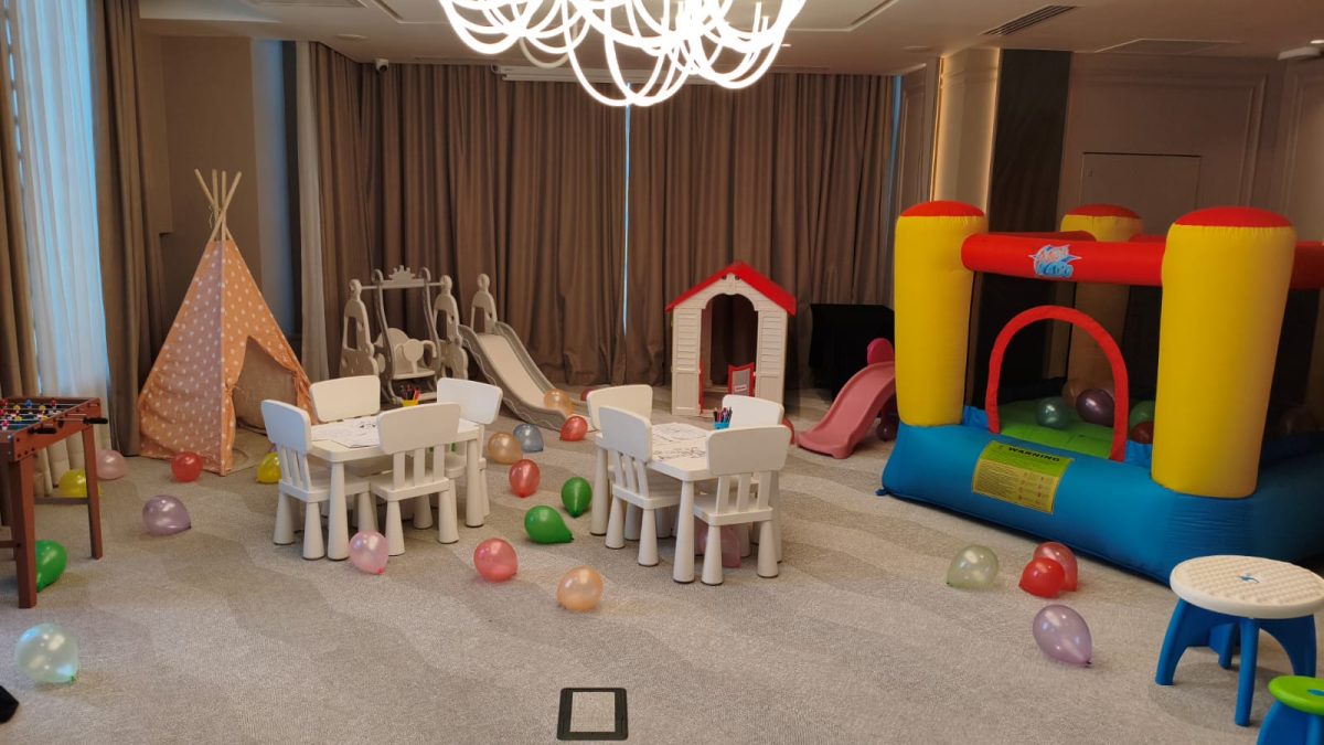 Interior cu colț de joacă: mese de desen, cort teepee, casuță, tobogane și gonflabil colorat