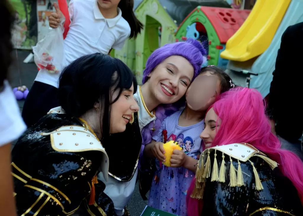 Animatoare Kids Mania în costume K-pop, apropiate de o fetiță, într-un loc de joacă
