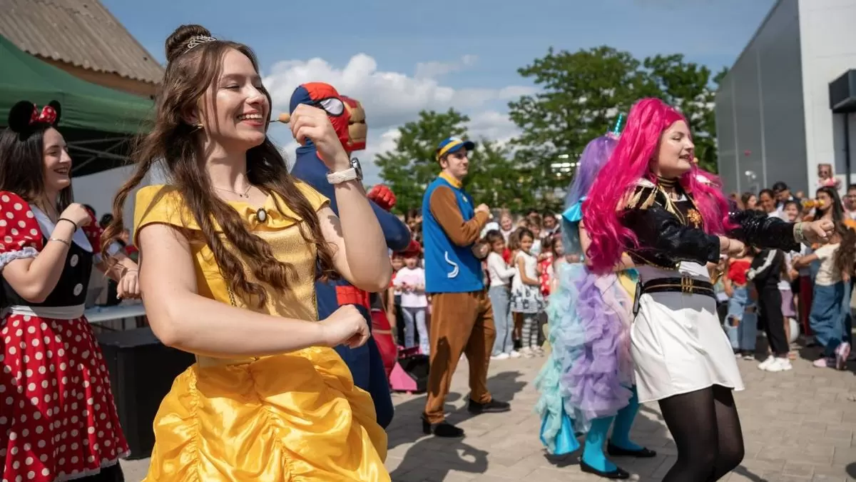 Belle și alte personaje dansând cu copiii la o petrecere în aer liber în Iași