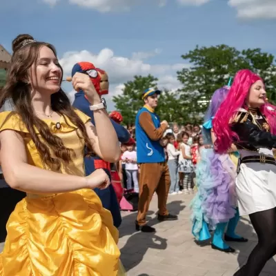 Belle și alte personaje dansând cu copiii la o petrecere în aer liber în Iași