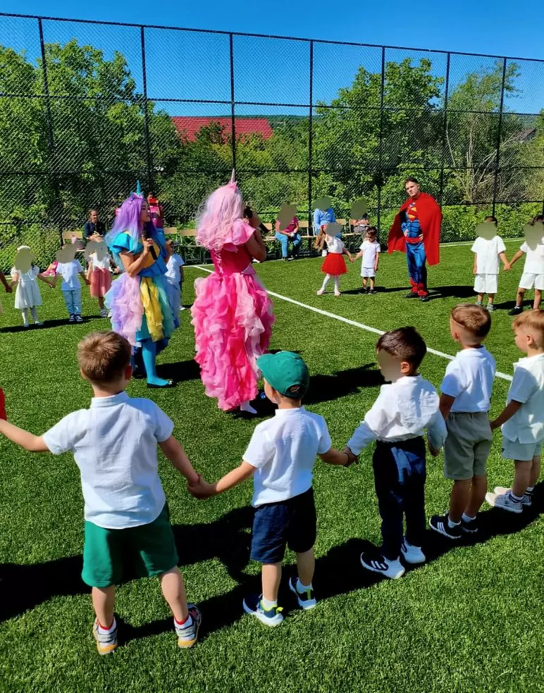 Copii prinși în horă cu animatorii Kids Mania, pe un teren de sport